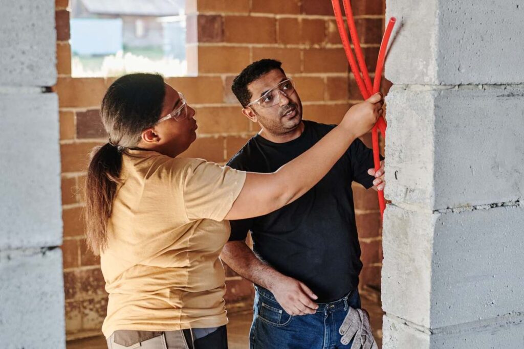 Deux individus examinent une colonne de béton armé sur un chantier
