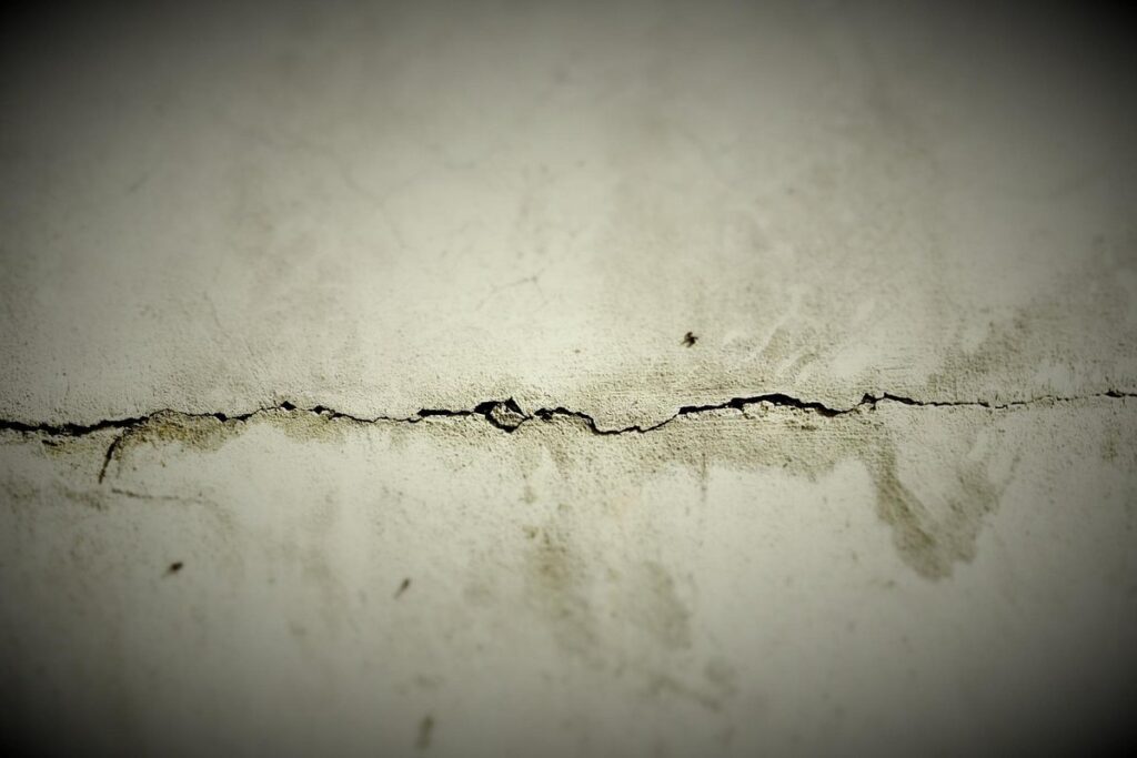 Fissure horizontale dans un mur blanc abîmé, texture granuleuse
