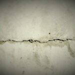 Fissure horizontale dans un mur blanc abîmé, texture granuleuse