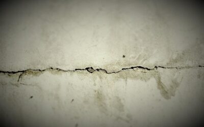 Fissure horizontale dans un mur blanc abîmé, texture granuleuse