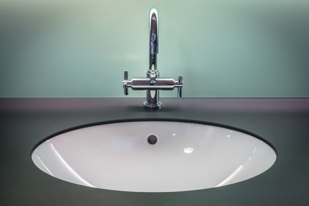 Lavabo blanc encastré avec robinet chromé à deux poignées sur mur gris