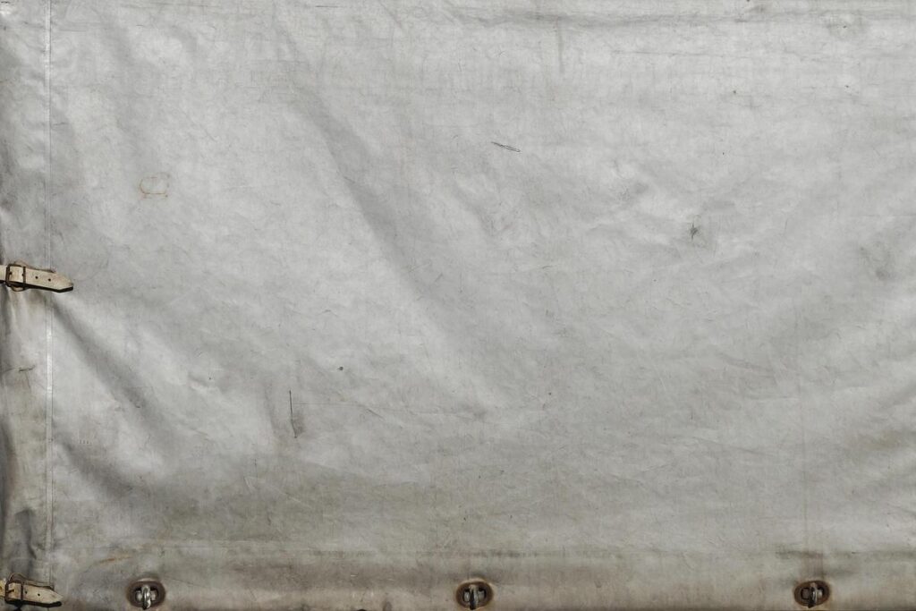 tissu gris usé avec sangles et œillets fixés sur bord inférieur