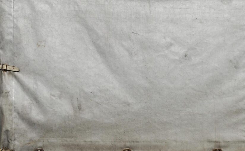 tissu gris usé avec sangles et œillets fixés sur bord inférieur