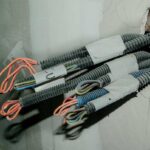 Câbles électriques sortant d'un trou dans un mur, avec des fils orange et bleu