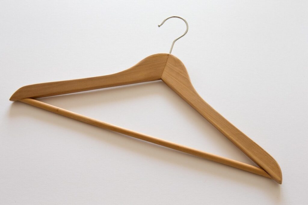 Cintre en bois suspendu, crochet métallique, fond blanc