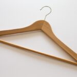 Cintre en bois suspendu, crochet métallique, fond blanc