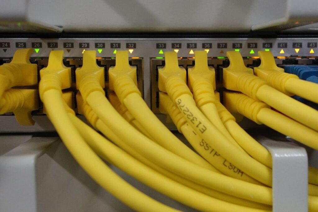 Câbles Ethernet jaunes branchés sur un panneau de brassage avec ports numérotés