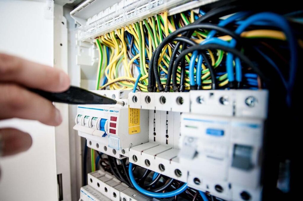 Une main utilise un tournevis pour vérifier le tableau électrique