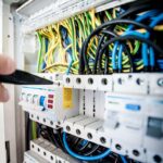 Une main utilise un tournevis pour vérifier le tableau électrique