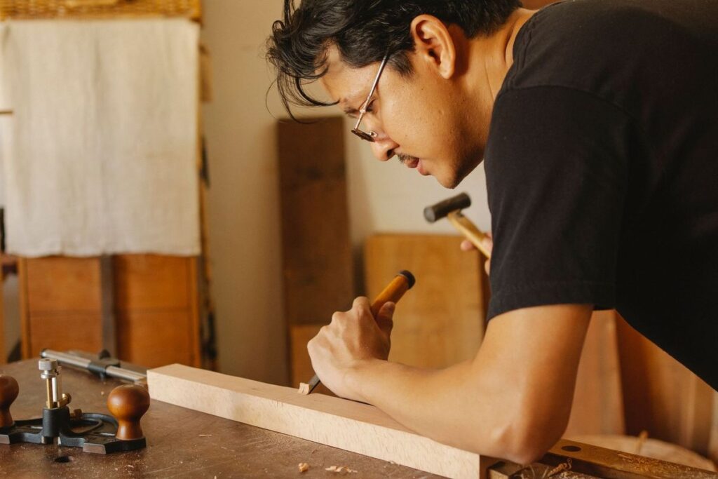 Artisan en train de sculpter du bois avec des outils manuels dans un atelier