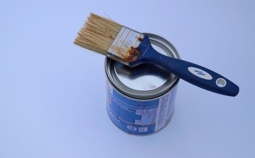Un pot de peinture avec un pinceau posé dessus