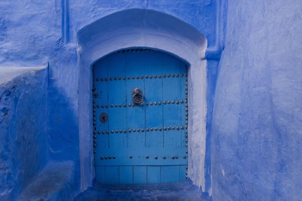 Porte bleue encadrée d'une arche, murs bleus texturés