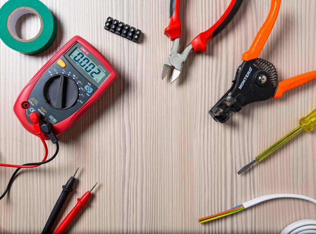 Outils de bricolage sur une table, incluant un multimètre, des pinces et un tournevis