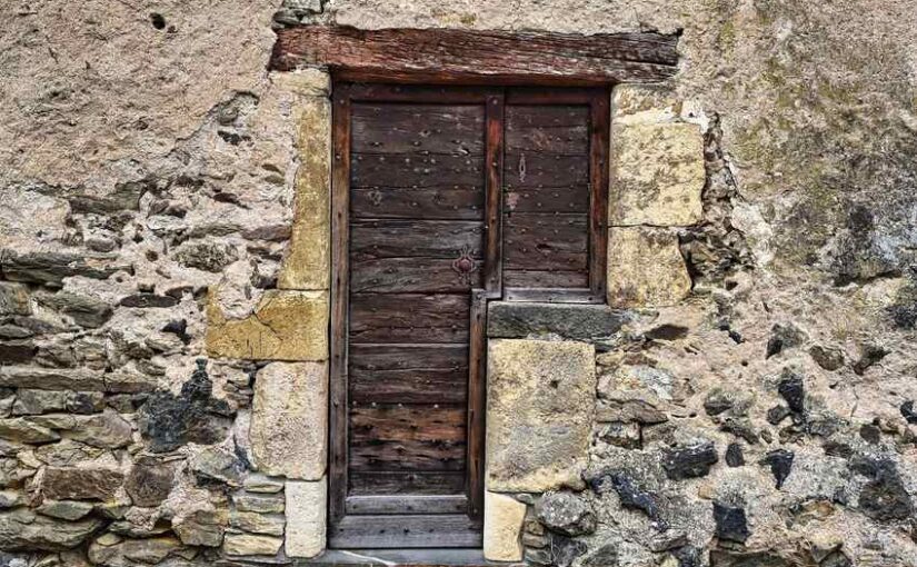 Porte en bois ancien dans un mur de pierre rustique