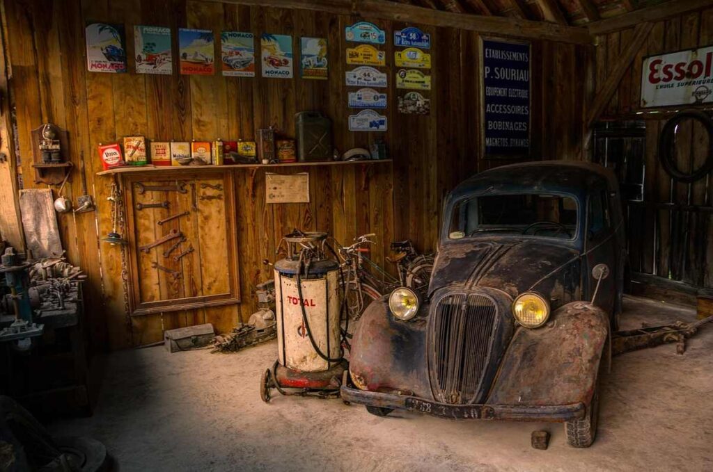 Ancien véhicule dans une petite garagère remplie d'objets vintage