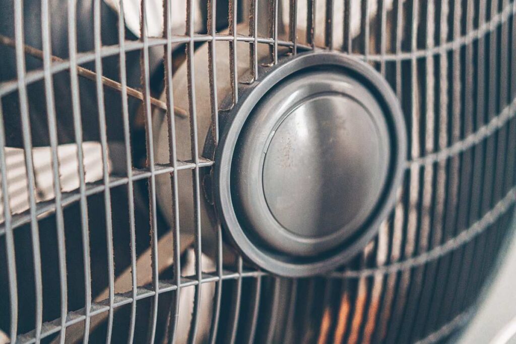 grille métallique recouvre un ventilateur en marche lame visible