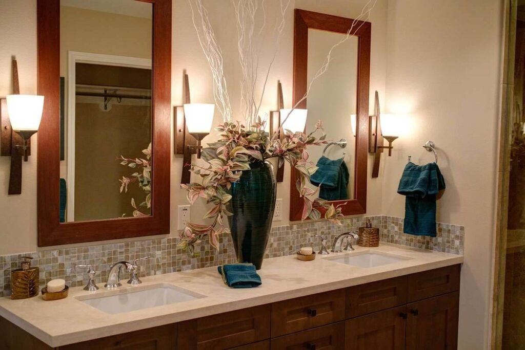 Salle de bain avec double vasque, miroirs encadrés bois, éclairage mural et carrelage