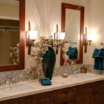 Salle de bain avec double vasque, miroirs encadrés bois, éclairage mural et carrelage