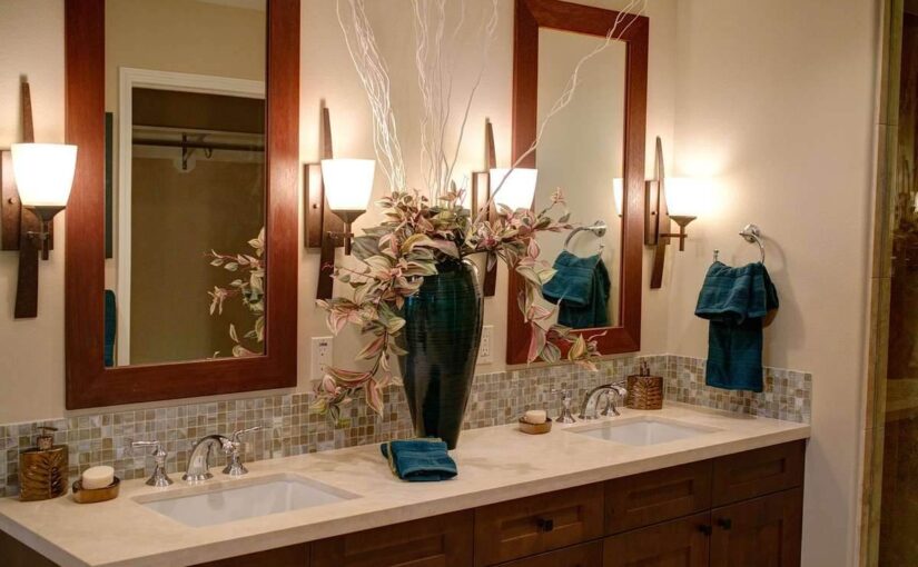 Salle de bain avec double vasque, miroirs encadrés bois, éclairage mural et carrelage