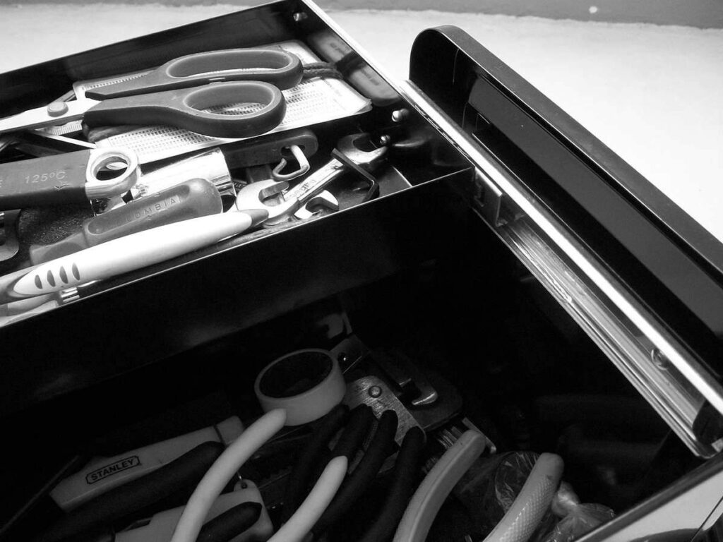 Boîte à outils ouverte avec divers outils, ciseaux et pinces visibles