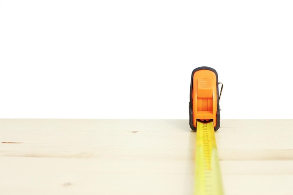Ruban à mesurer jaune déployé horizontalement sur une surface de bois clair
