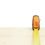 Ruban à mesurer jaune déployé horizontalement sur une surface de bois clair