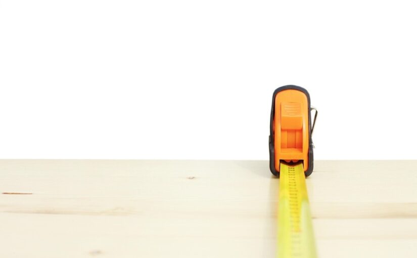 Ruban à mesurer jaune déployé horizontalement sur une surface de bois clair