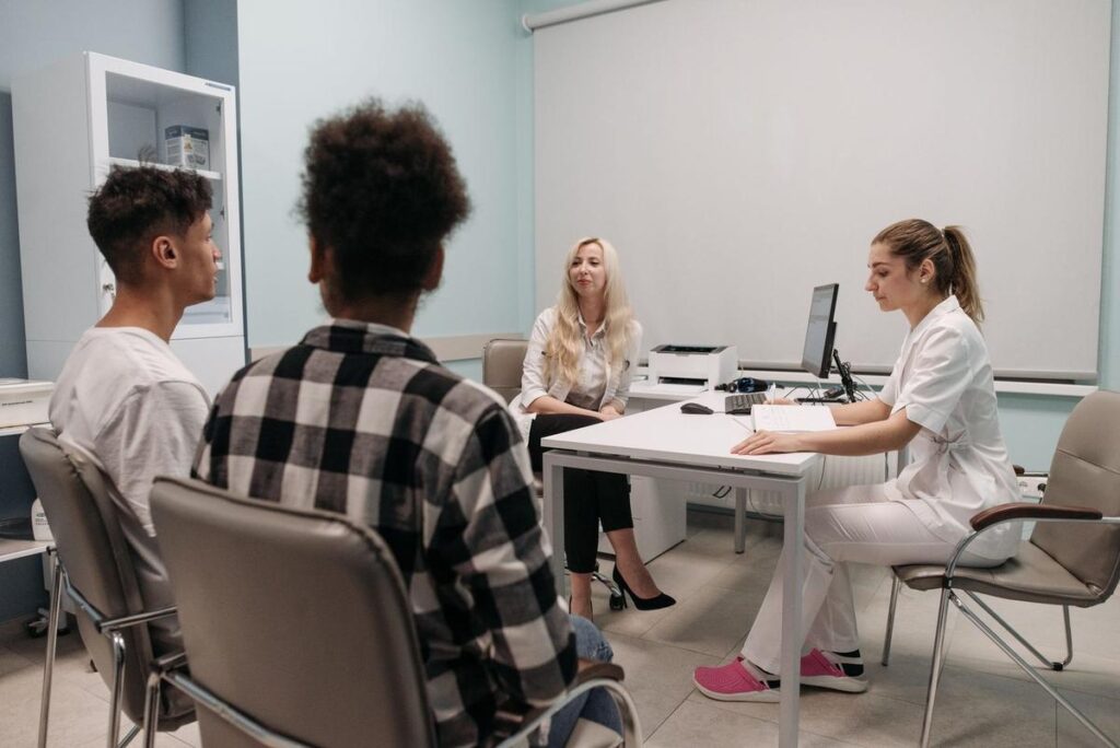 Professionnels en réunion dans un bureau, discutant autour d'une table avec ordinateurs