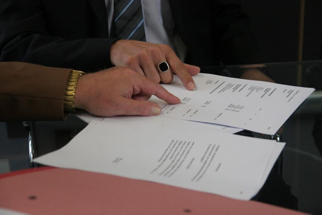 Mains sur des papiers, montre et anneau noir, réunion professionnelle