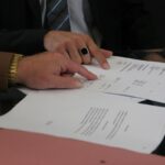 Mains sur des papiers, montre et anneau noir, réunion professionnelle