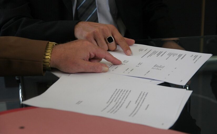 Mains sur des papiers, montre et anneau noir, réunion professionnelle